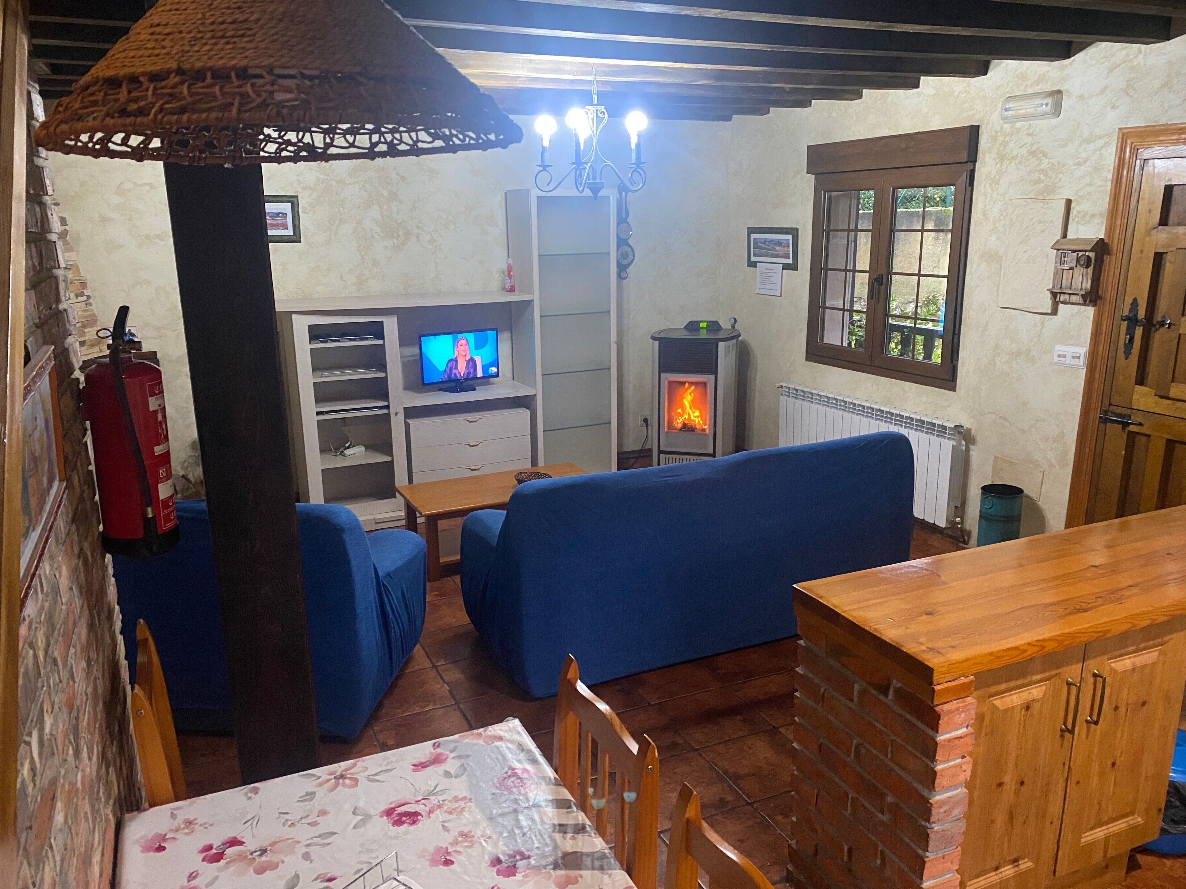A cozy room with a fireplace, blue seating, a television, and a wooden table.