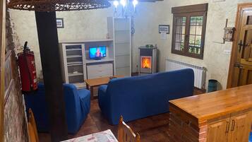 A cozy room with a fireplace, blue seating, a television, and a wooden table.