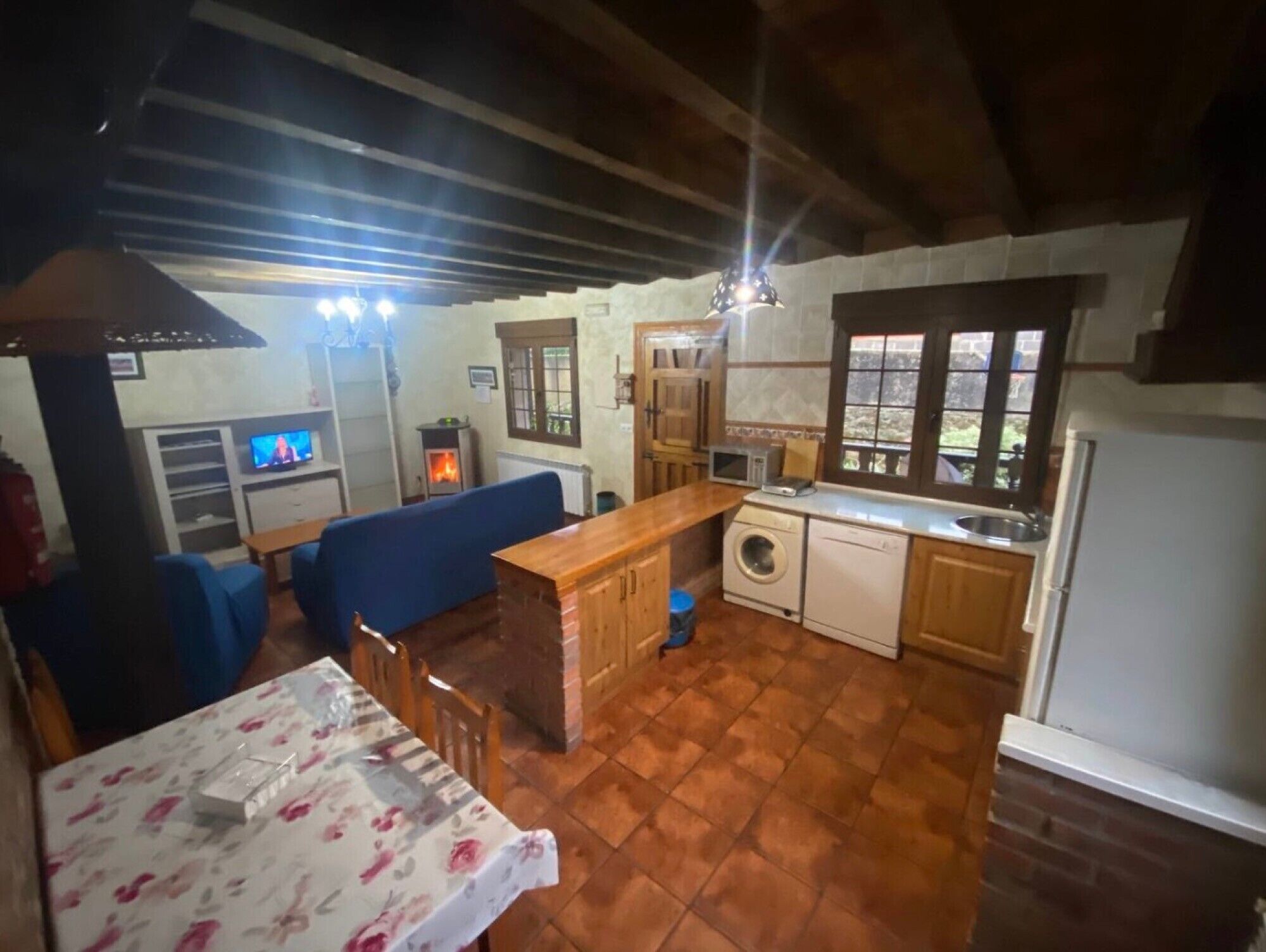 A compact living space with a sofa, a small table, a washing machine, a microwave, and a sink.