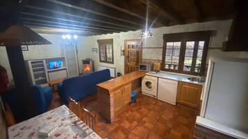 A compact living space with a sofa, a small table, a washing machine, a microwave, and a sink.