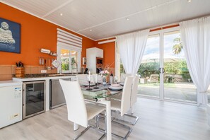 A modern kitchen with a dining area, a Buddha statue, and a view of the garden.