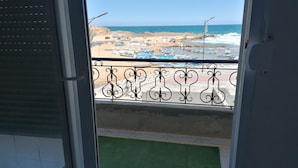 A balcony with a view of a beach, featuring a metal railing and a green carpet. - HOTEL NASSMA residence  (Jijel)