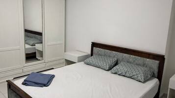 Un dormitorio con una cama, un armario y una mesita de noche.