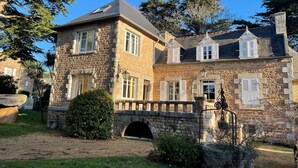 A stone building with a brick facade, multiple windows with shutters, and a stone bridge leading to the entrance. - Villa 'Magnifique  À 80m Des Plages' with Private Terrace, Private Garden and Wi-Fi (Trébeurden)