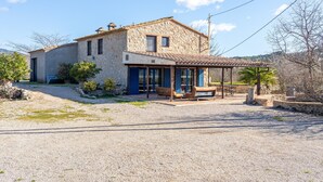 A stone house with a patio, a covered seating area, and a view of the surrounding landscape.