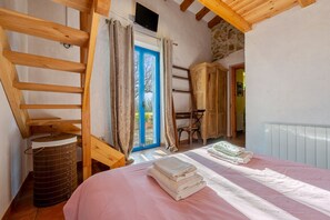 Une chambre à coucher avec un lit, une échelle en bois, une armoire et une fenêtre avec des rideaux.