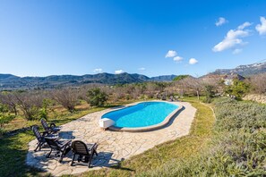 Une piscine avec des chaises longues et une terrasse en pierre.