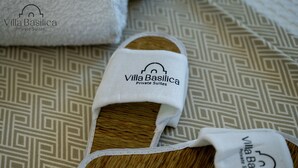 Badeschlappen der Villa Basilica Private Suites mit Stoffhintergrund in geometrischem Muster.