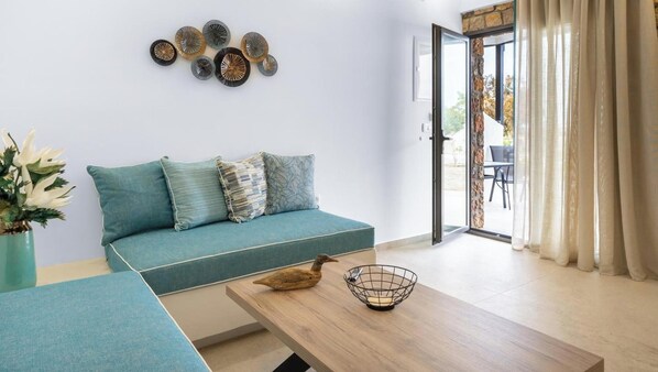 Ein modernes Wohnzimmer mit einem türkisfarbenen Sofa, einem Holztisch und dekorativer Wandgestaltung.