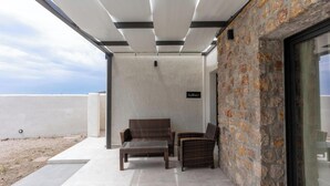 An outdoor seating area with wicker furniture, a stone wall, and a clear view of the sky.