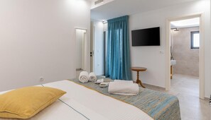 Ein Hotelzimmer mit Bett, Fernseher, Badezimmer und kleinem Tisch.