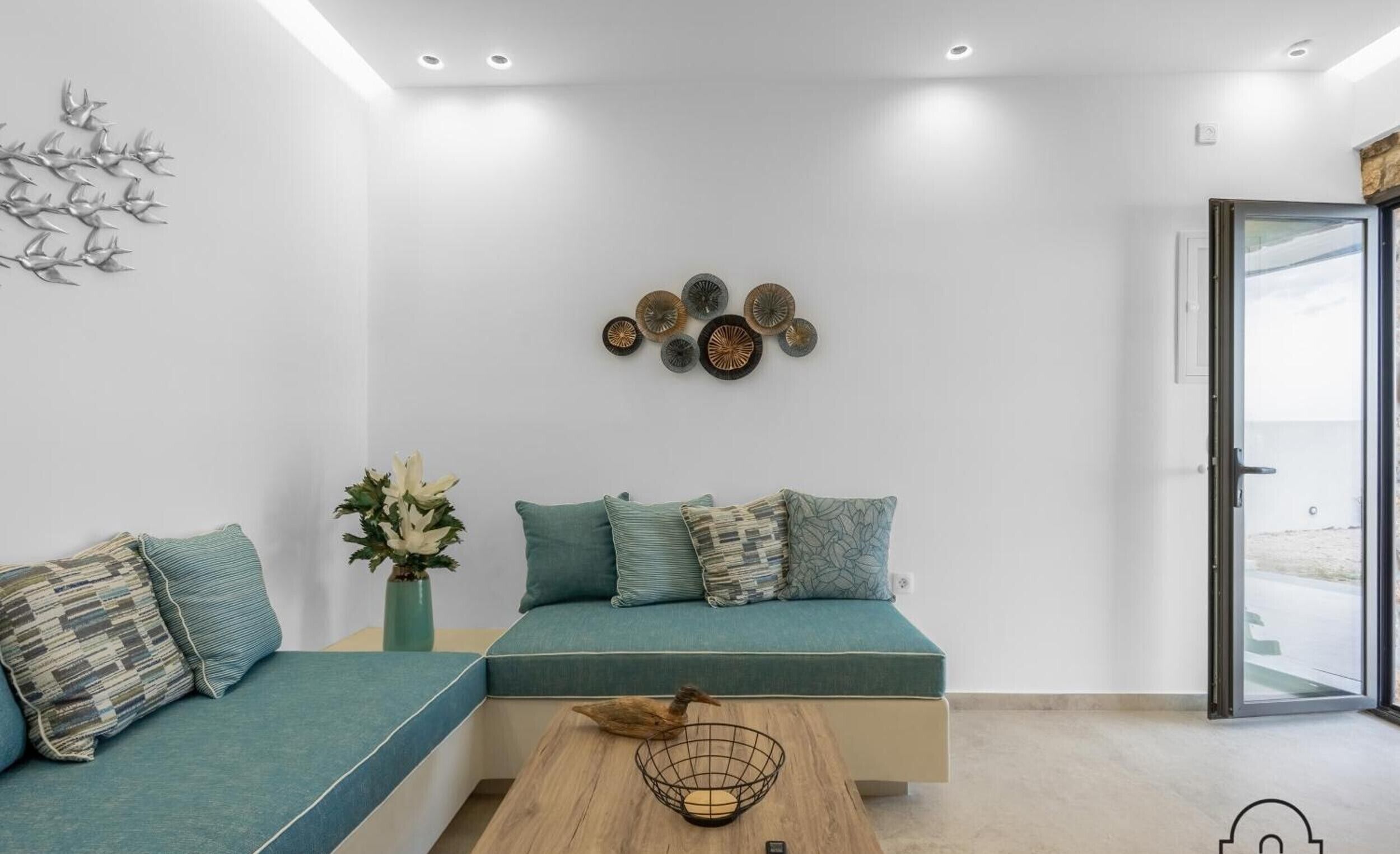 Una sala moderna con un sofá modular, decoración en la pared y vistas a través de un ventanal.