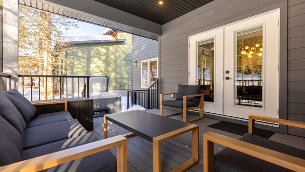 A covered outdoor seating area with a sofa, chairs, and a table.