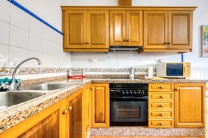 Una cucina con mobili in legno, un lavello in acciaio inossidabile, un forno a microonde ed una lavastoviglie.