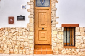 Una porta in legno con un piccolo oblò e un muro in pietra.