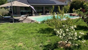 Een modern huis met een zwembad, een overdekte patio en zonnepanelen op het dak.
