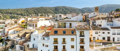 Una zona urbana densamente poblada con edificios blancos, una torre destacada y un paisaje montañoso de fondo.