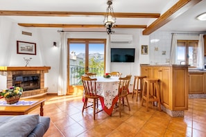 Un comedor con mesa y sillas, chimenea y cocina con armarios de madera.
