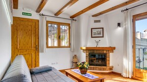 Una habitación con sofá, una mesa con cesta, chimenea y una puerta que indica 'SALIDA'.