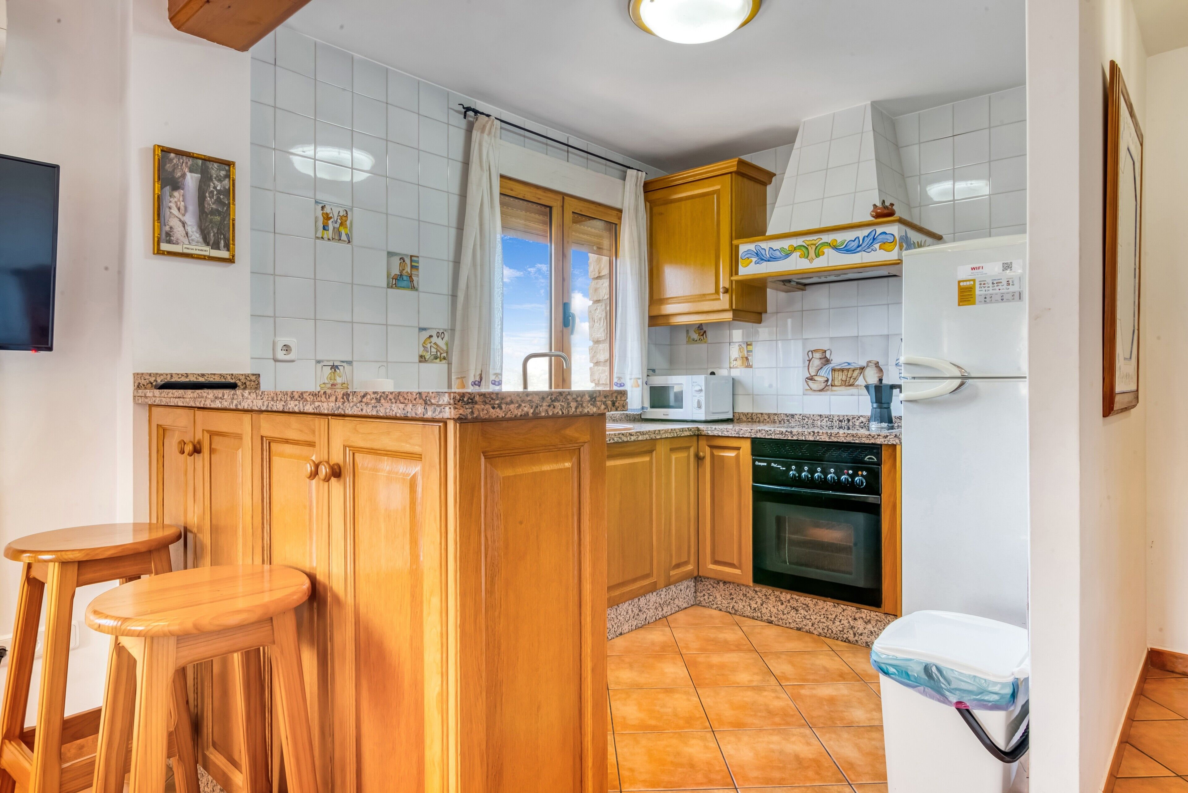 A kitchen with wooden cabinets, a microwave, a refrigerator, and a sink.