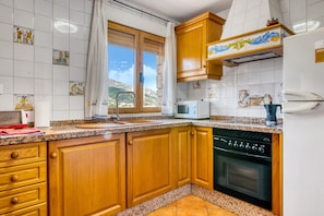 A kitchen with wooden cabinets, a microwave, a dishwasher, and a window with a view of the mountains.
