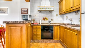 Une cuisine avec des meubles de rangement en bois, un four encastré, un four à micro-ondes et un dosseret carrelé.