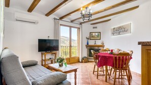 Un salon comprenant un canapé, un téléviseur, une table à manger avec des chaises, une cheminée et un balcon avec vue.