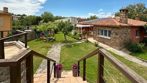 Un barrio residencial con una casa de piedra, una zona de juegos infantiles y una escalera que lleva a un balcón.