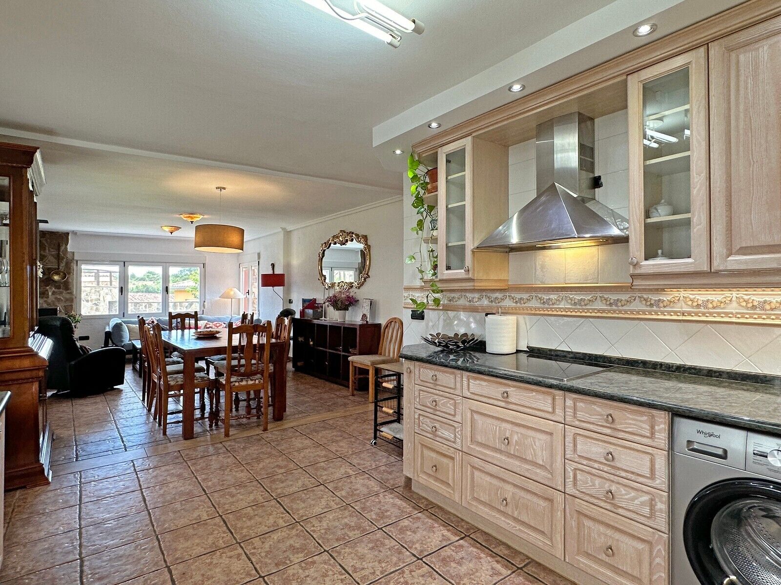 A spacious kitchen with a built-in washer, wooden cabinets, and a dining area with chairs.
