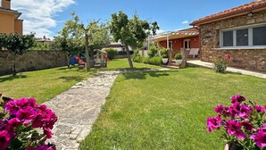 Un barrio residencial con un sendero de piedra, un parque infantil y una casa de fachada de piedra.