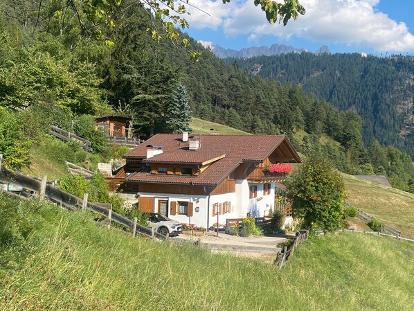 A traditional chalet with a sloped roof, wooden balconies, and a view of a mountainous landscape.