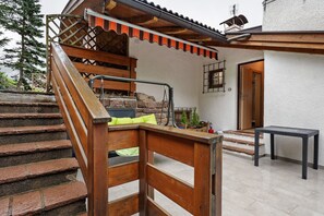 A wooden staircase leading to a covered outdoor area with a table and a door.