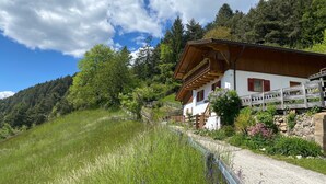 A traditional chalet with a wooden balcony, surrounded by lush greenery and a clear sky. - Apartment 'Leitner' with Mountain View, Private Terrace and Wi-Fi (Tiers)