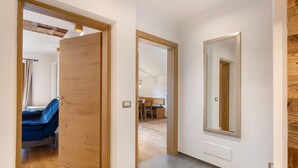 A hallway with a wooden door, a mirror, and a view into a room with a bed and a chair. - Apartment 'Leitner' with Mountain View, Private Terrace and Wi-Fi (Tiers)