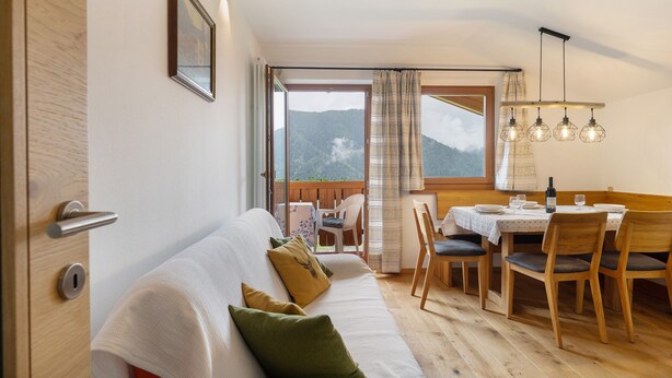 A cozy room with a sofa, dining table, chairs, and a view of mountains. - Apartment 'Leitner' with Mountain View, Private Terrace and Wi-Fi (Tiers)