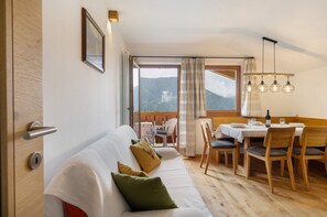 A cozy room with a sofa, dining table, chairs, and a view of mountains. - Apartment 'Leitner' with Mountain View, Private Terrace and Wi-Fi (Tiers)