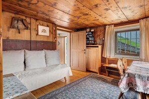 A wooden interior with a sofa, a table, and a window with curtains.