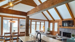 Une cuisine spacieuse avec un grand îlot central, des poutres en bois et une cheminée.