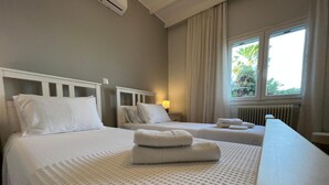 Une chambre d’hôtel avec deux lits, une fenêtre avec des rideaux, un radiateur et une lampe.