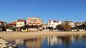 A waterfront property with multiple buildings, a boat dock, and a sandy beach.