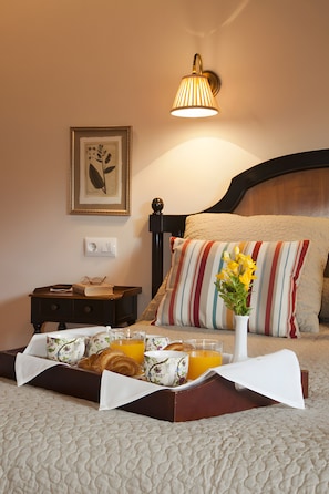 A neatly made bed with a striped pillow, a bedside table with a book and glasses, and a tray with croissants and orange juice. - Country House 'Tierra' with Private Terrace, Private Garden and Wi-Fi (Llanes)