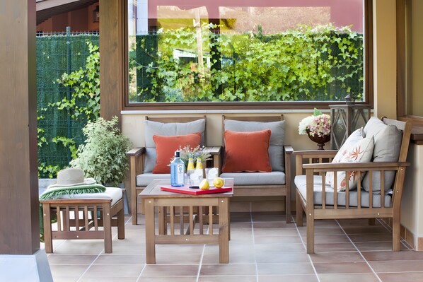 A patio area with a wooden bench, a table with a red tray, and a sofa with cushions.