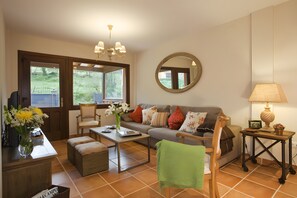 A living room with a sofa, chairs, a coffee table, a lamp, and a mirror.