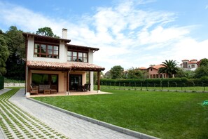 A two-story house with a patio, a well-maintained lawn, and a clear sky.