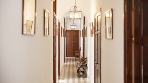 A hallway with a patterned floor, wooden doors, and framed pictures on the walls.