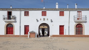A white building with red doors and windows, a balcony, and a clear sky.