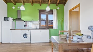 Une cuisine équipée d’un lave-linge, d’un four à micro-ondes et d’une fenêtre donnant sur une maison.
