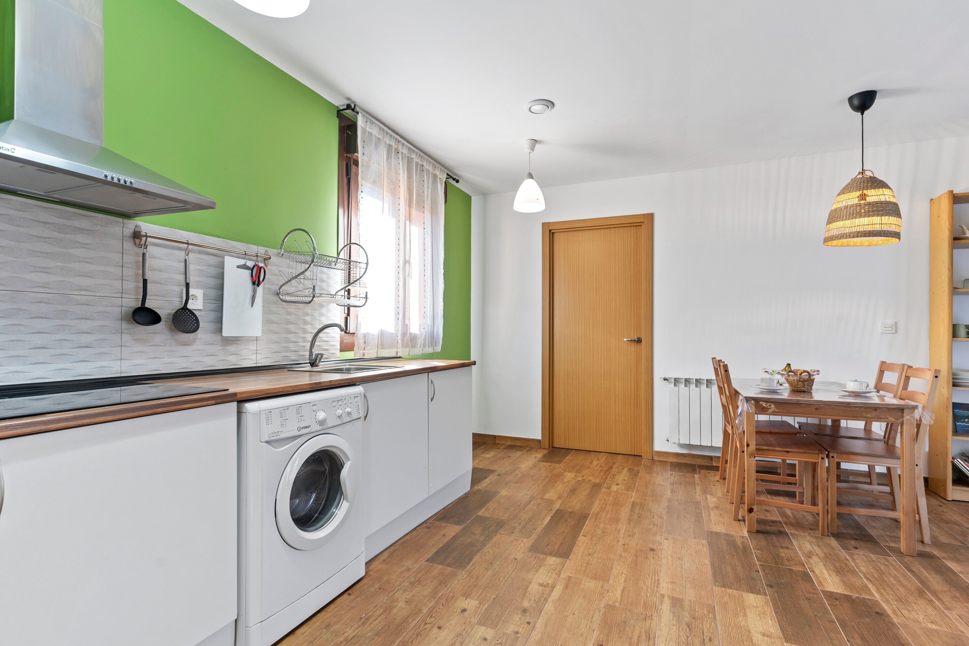 Une cuisine équipée d’un lave-linge, d’une table à manger en bois et de chaises.