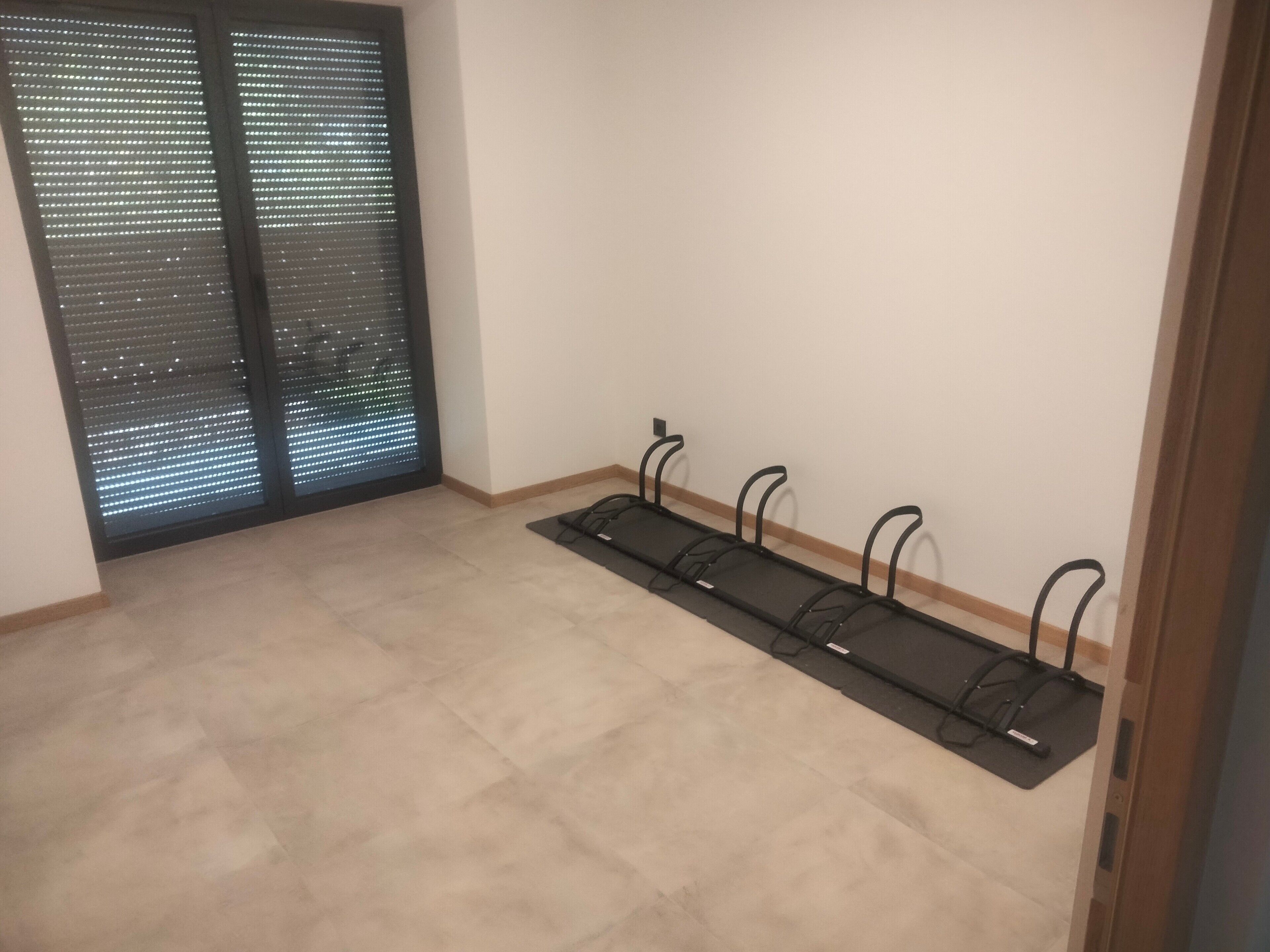 A room with a large window, a black metal rack, and a beige carpet.
