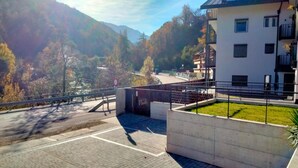 Edifício com entrada pavimentada, portão de metal e vista para uma paisagem montanhosa.